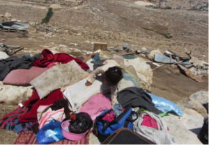A girl climbs on top of belongings that were in illegal structures in the Bedouin Al-Khdeirat community. (Photo credit: B'TSELEM)