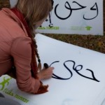 אישה כותבת על שלט את המילה "זכותי" בערבית. צילום: תום רביב